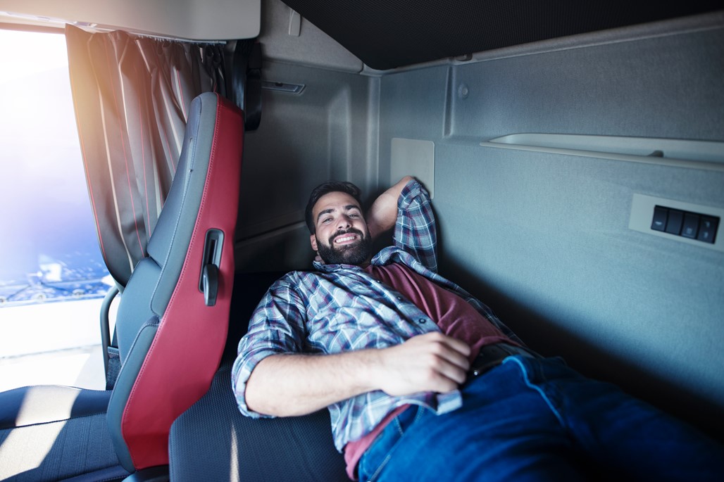 A driver taking a lay down in the bed within the lorry.